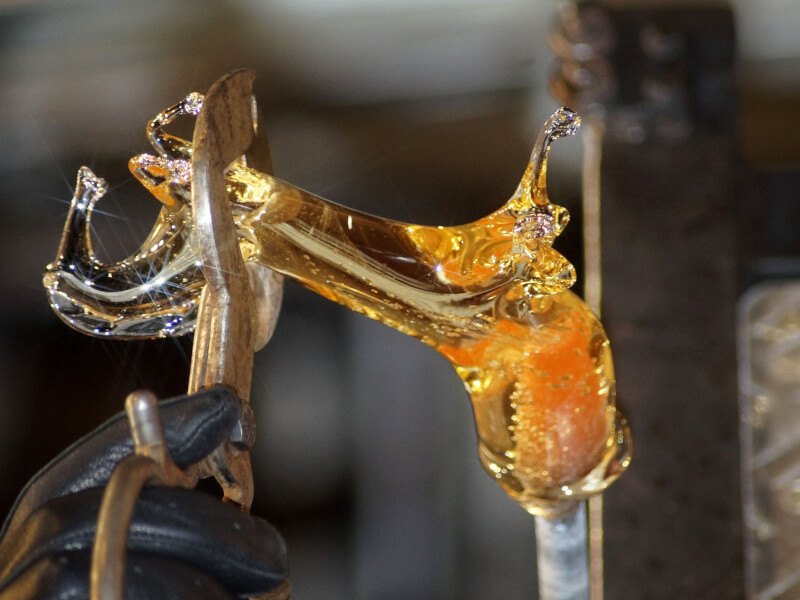 A person makes glass art with molten glass.